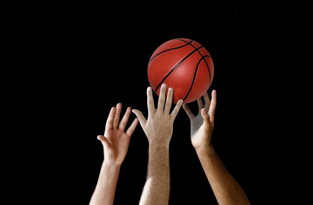 Mains tendues vers un ballon de basket